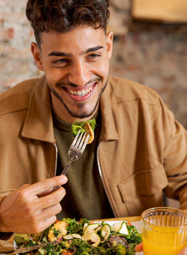 Un ragazzo sorride mentre mangia un'insalata gluten free